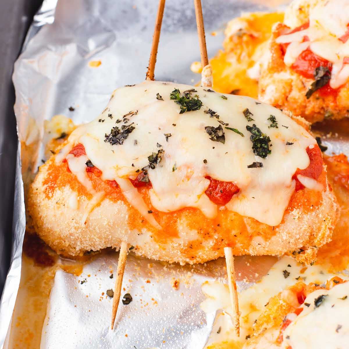 a close up shot of a piece of Pizza Chicken with bamboo skewers