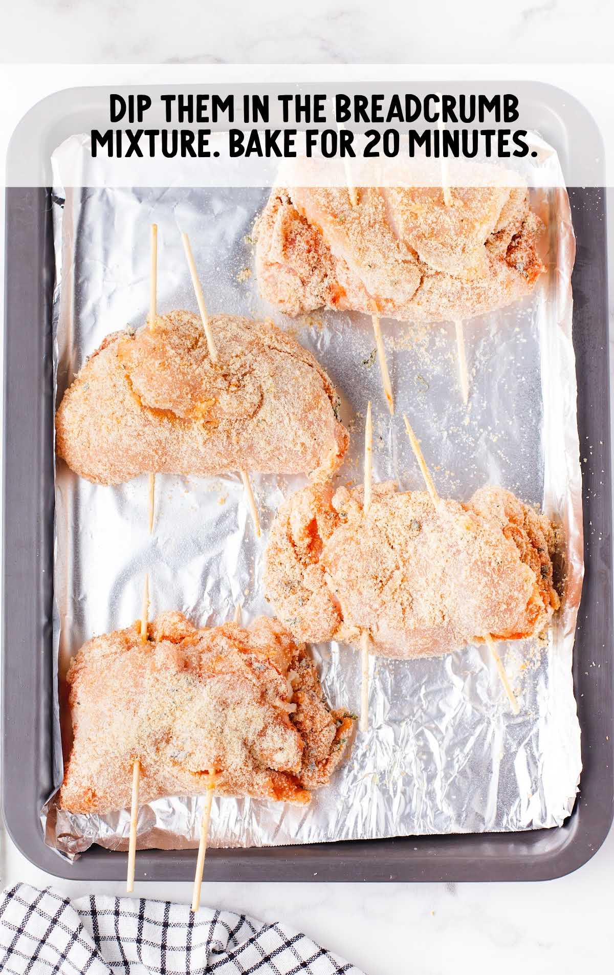chicken breast dipped in breadcrumb on a baking pan