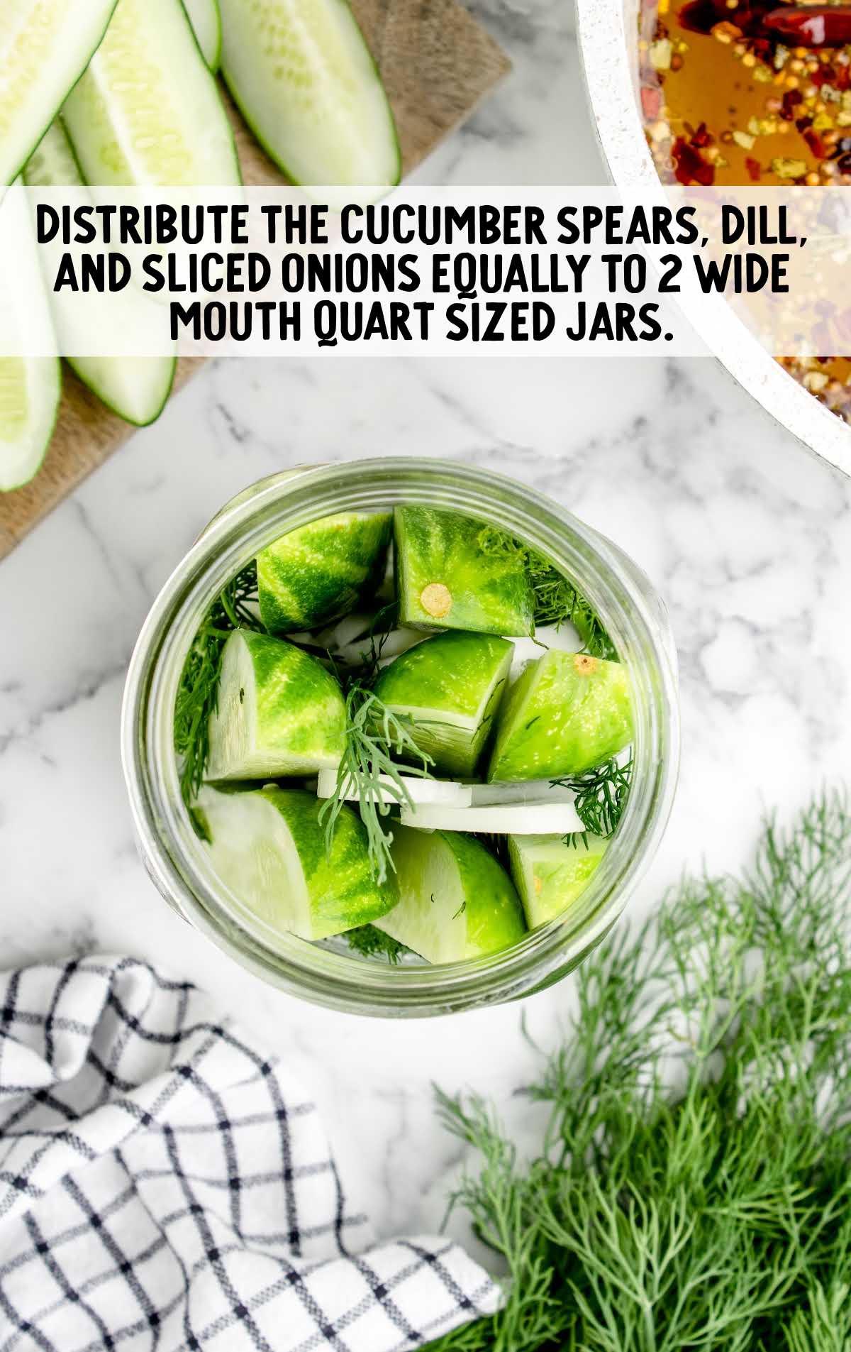 cucumbers spears, dill, and sliced onion placed in a jar