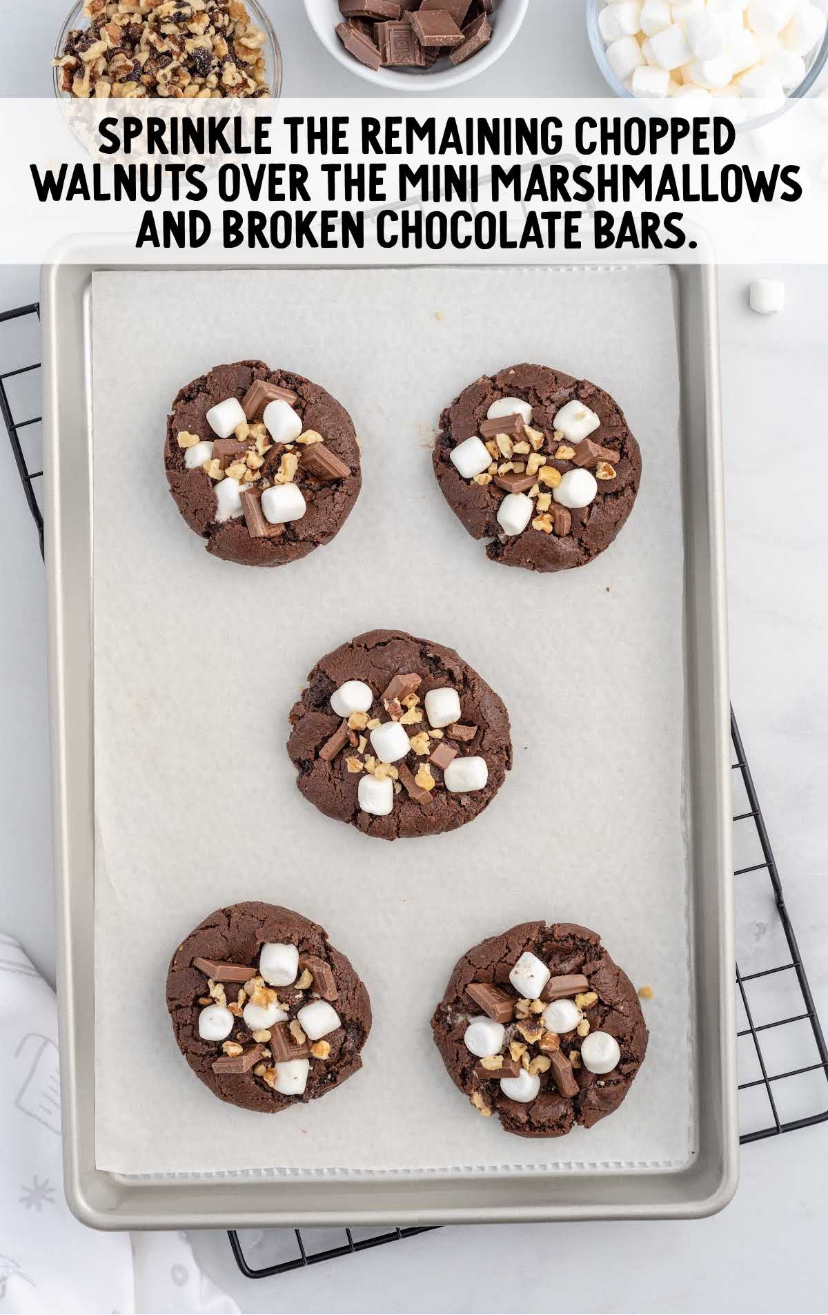walnuts sprinkled over the marshmallows and chocolate bars on a baking sheet