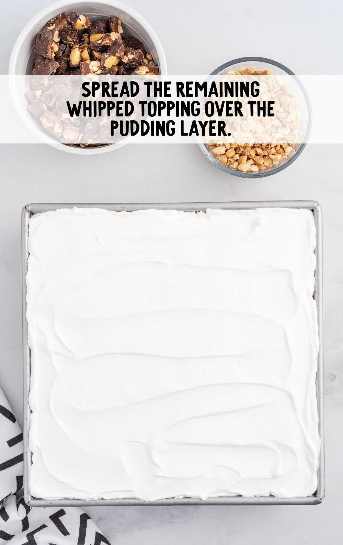 whipped topping spread over the pudding layer in a baking dish