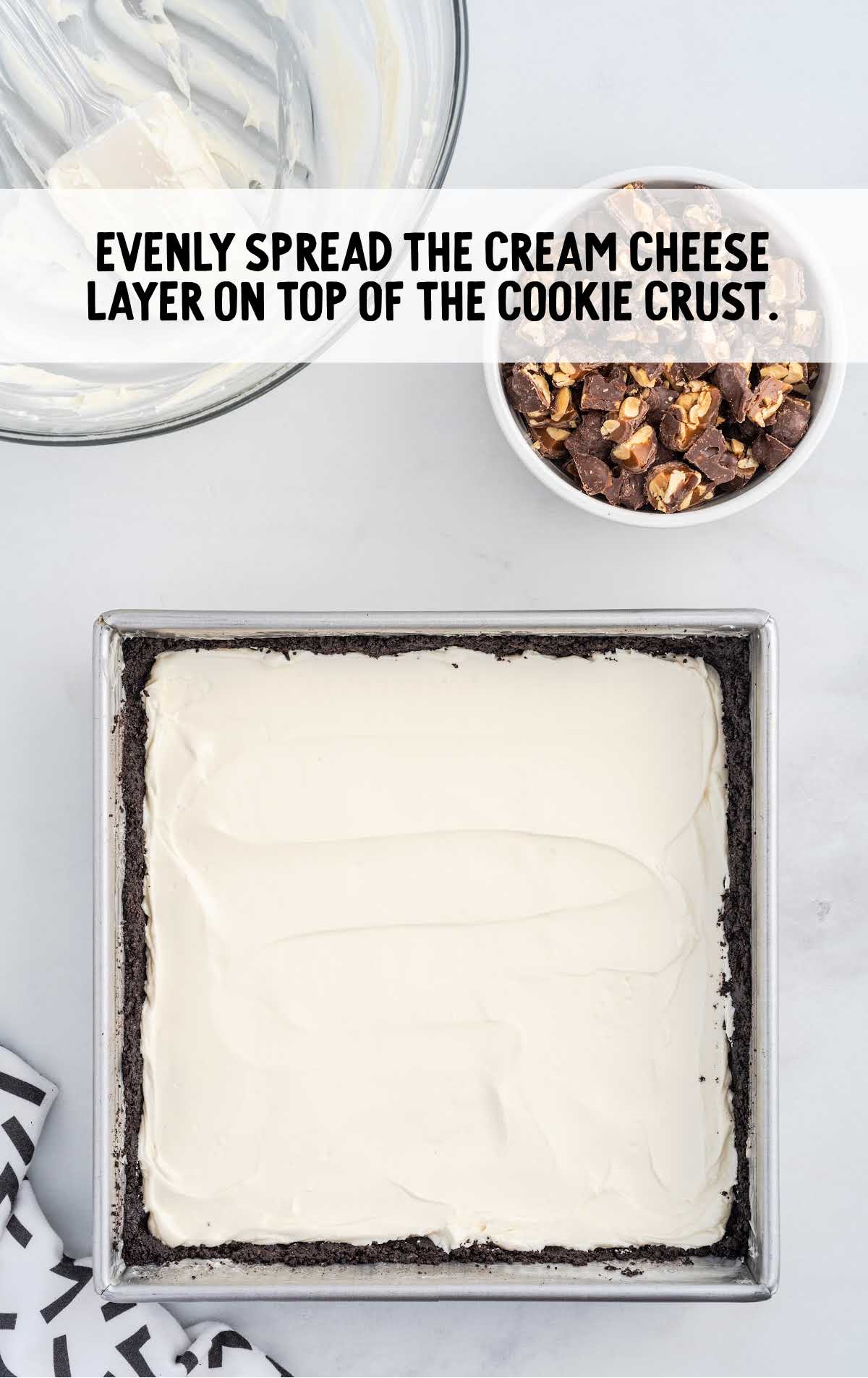 cream cheese layers spread on top of the cookie crust in a baking dish