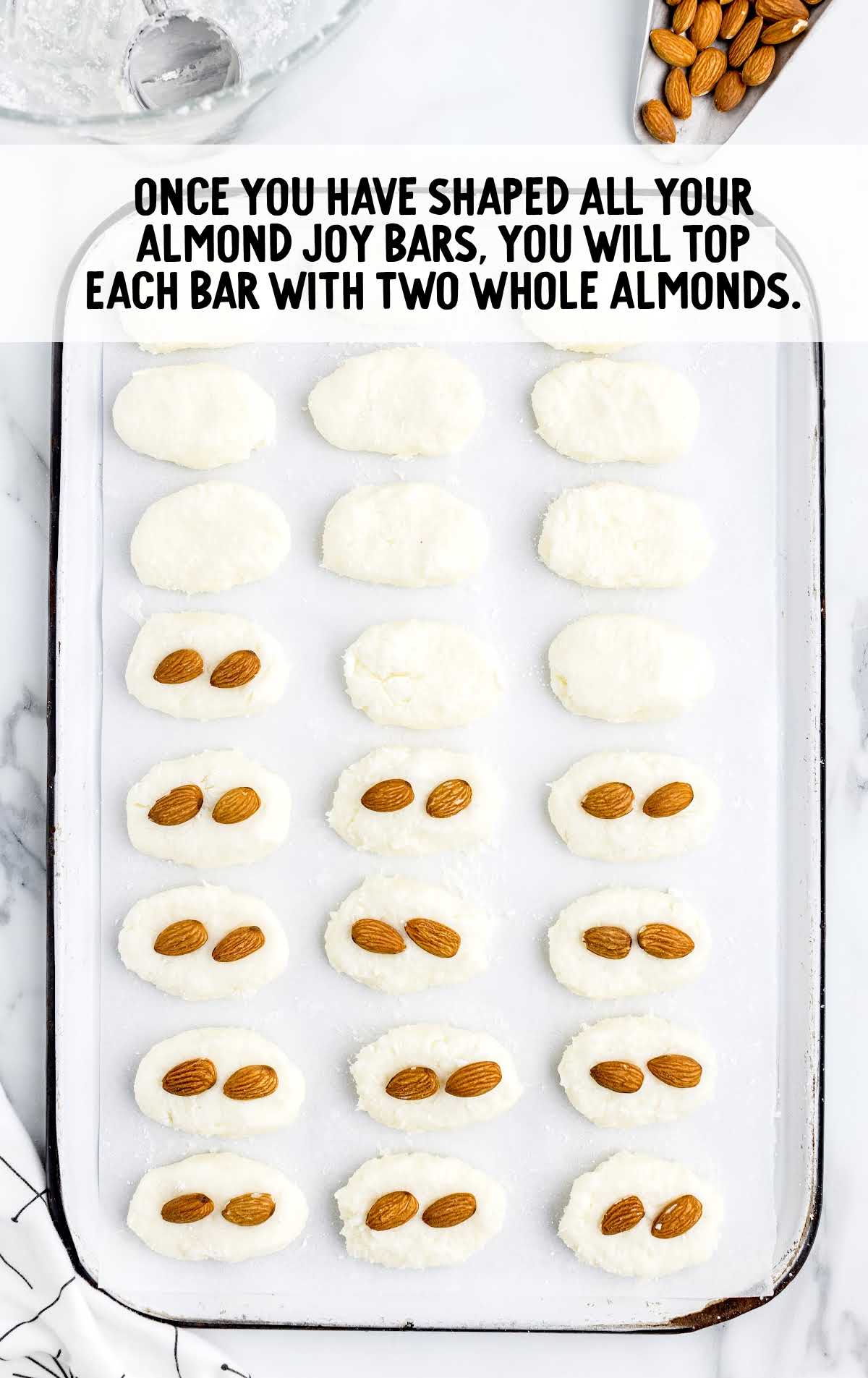 top each bar with a whole almond on a baking tray