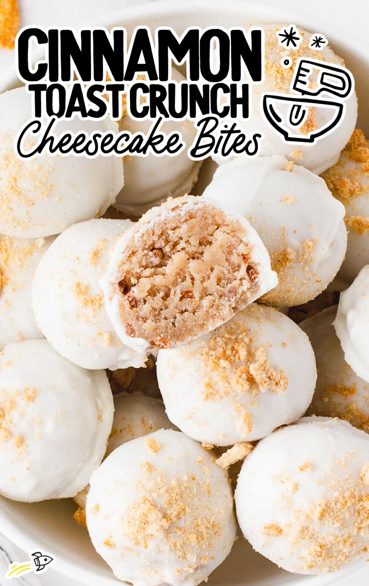 overhead shot of Cinnamon Toast Crunch Cheesecake Bites with one having a bite taken out of it in a bowl