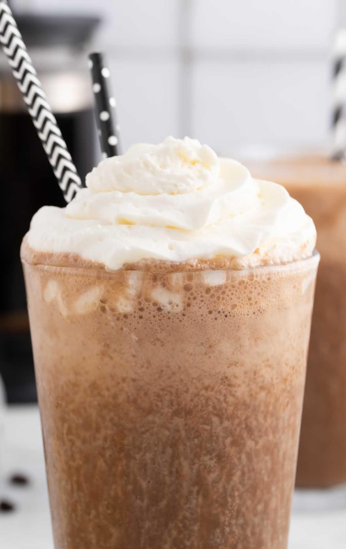 close up shot of coffee smoothie in a glass topped with whipped cream