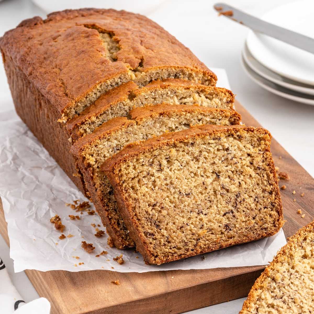 a close up shot of Banana Bread with slices cut on a wooden cutting board