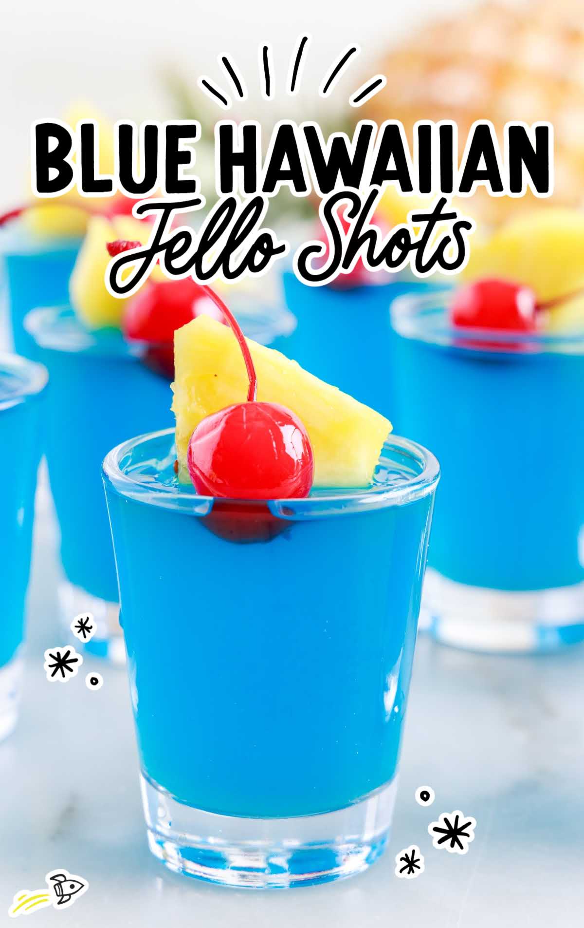 a close up shot of a Blue Hawaiian Jello Shot topped with a cherry and slice of pineapple