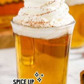 a close up shot of Cinnamon Roll Fireball Shot in a cup topped with whipped cream