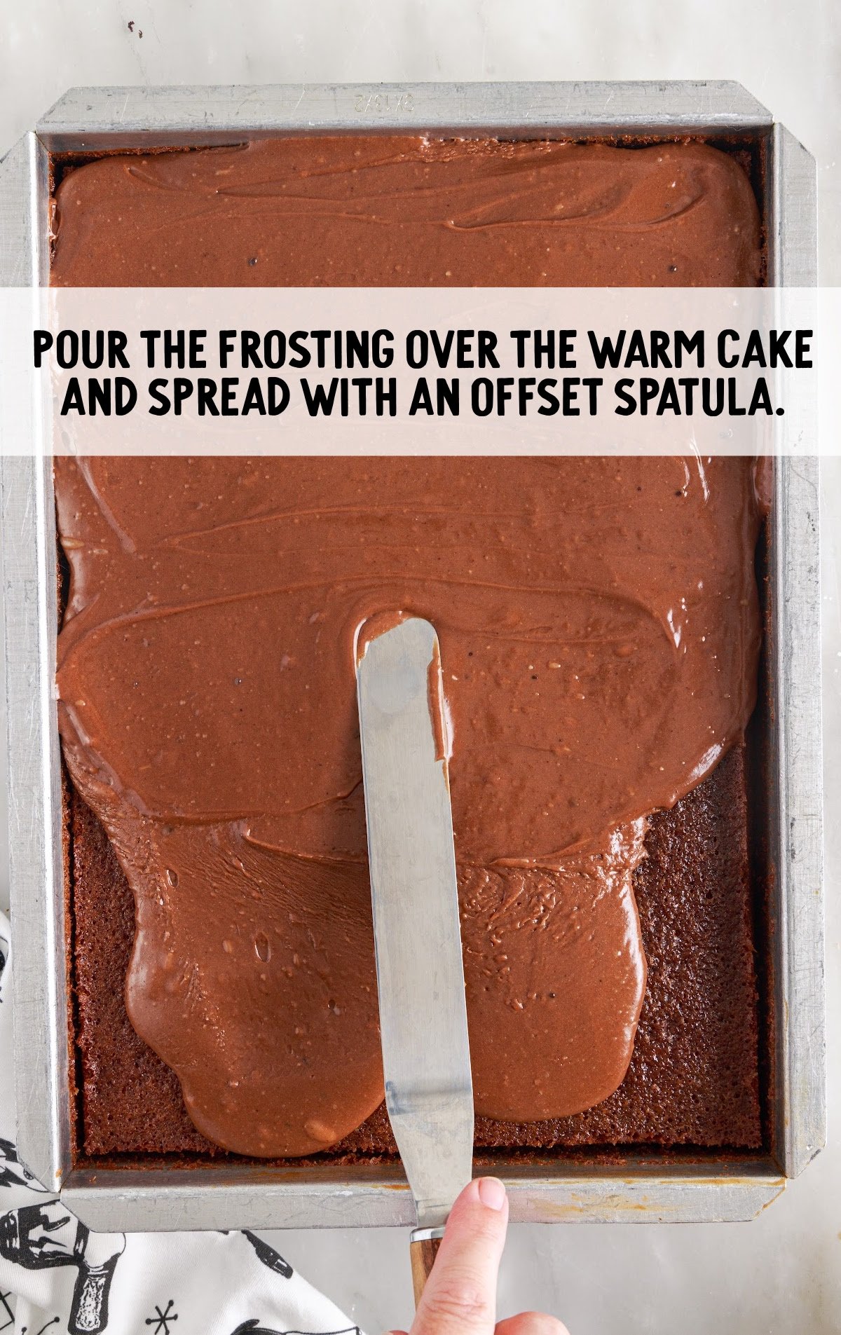 frosting poured over the cake and spread with spatula on a baking dish