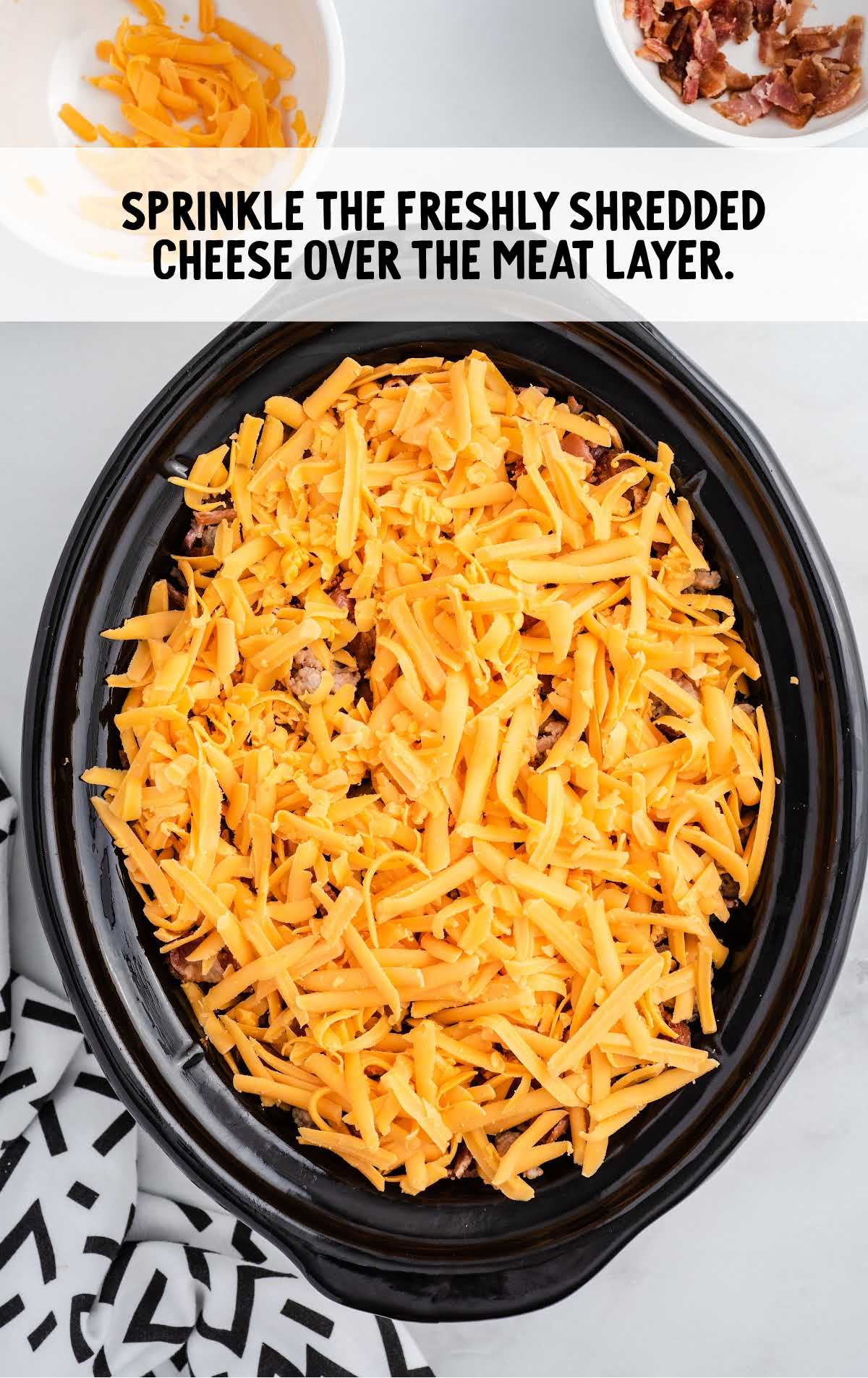 fresh shredded cheese sprinkled over the meat layer in a crockpot