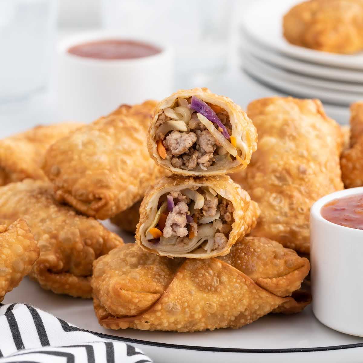 a close up shot of Homemade Egg Rolls with one split in half on a plate