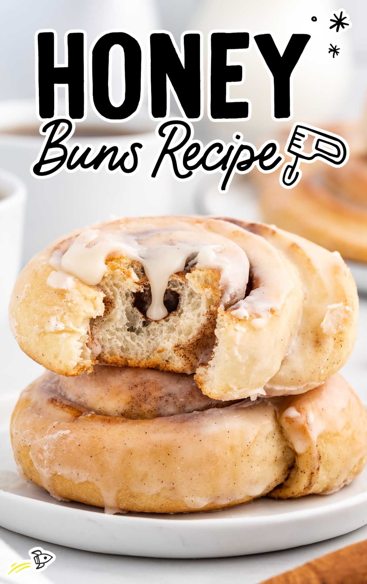 close up shot of Honey Buns stacked on another honey bun with a bite taken out of it on a plate