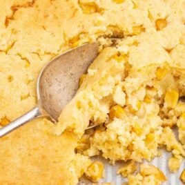 close up shot of Jiffy Corn Casserole with a piece taken out and a spoon getting a piece