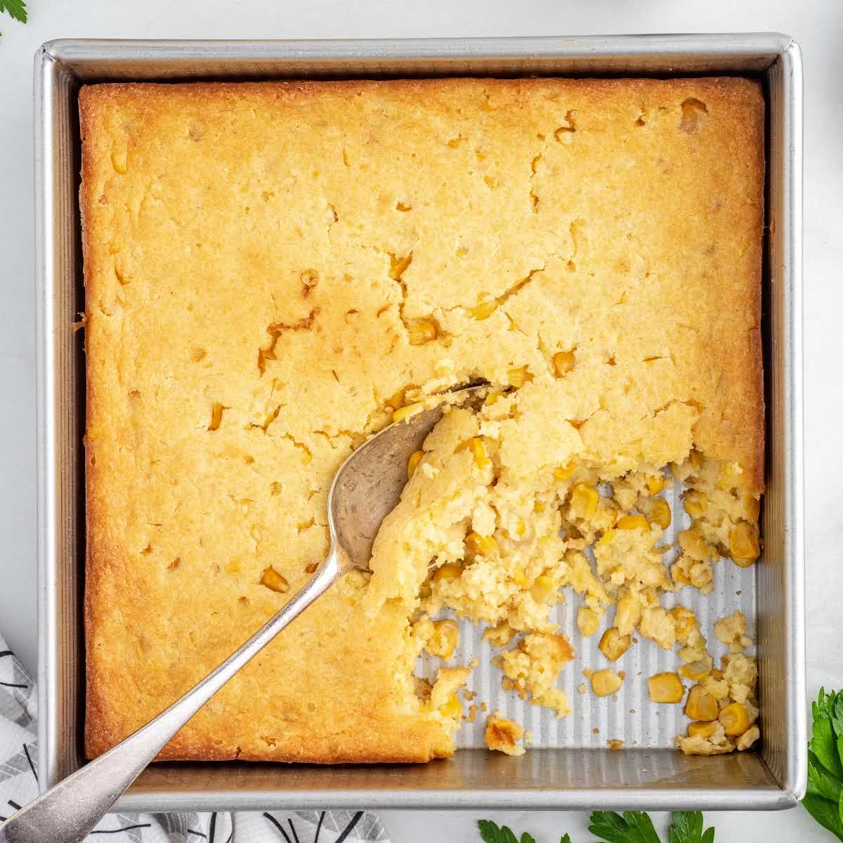 overhead shot of Jiffy Corn Casserole with a piece taken out and a spoon getting a piece