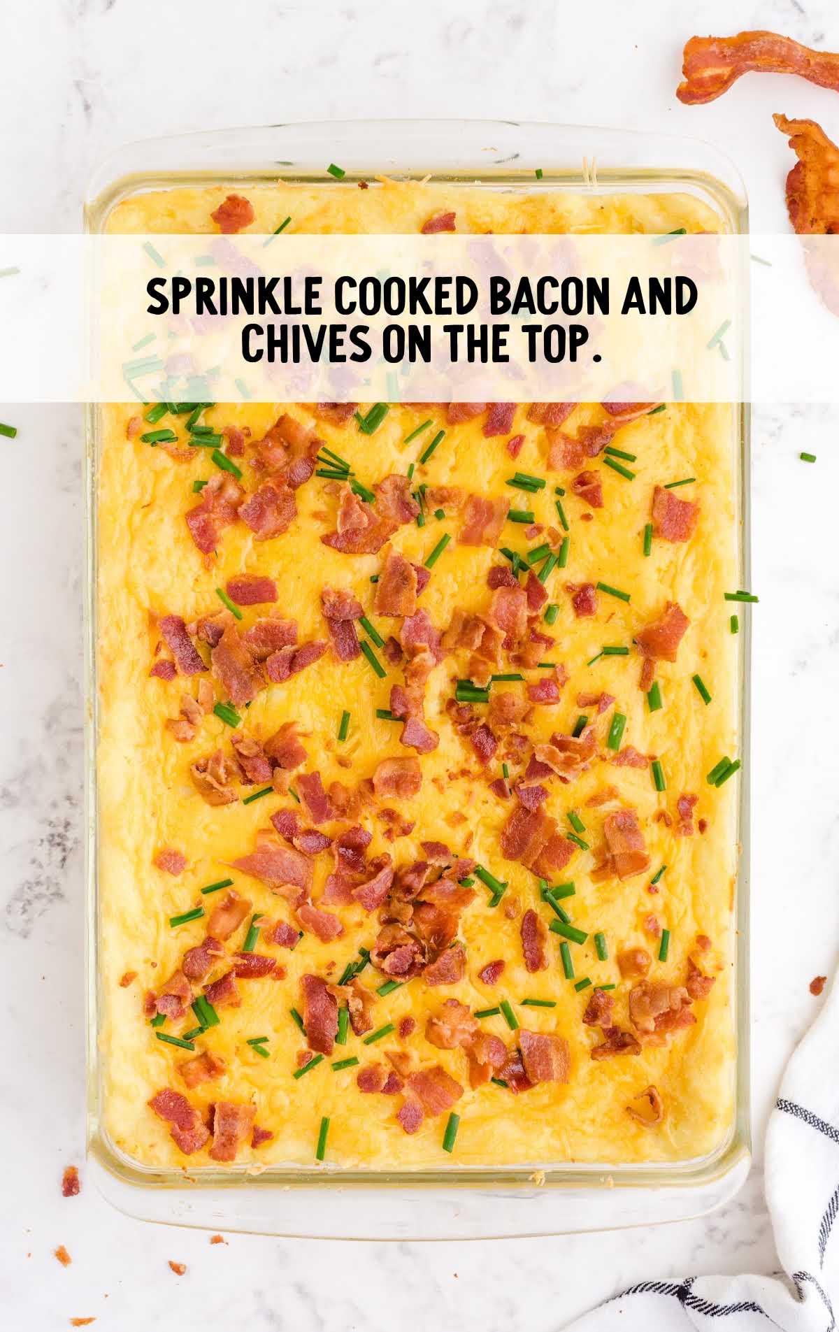 cooked bacon and chives sprinkled on top of the casserole