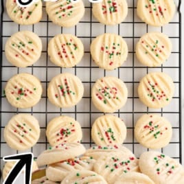 Round Christmas Shortbread Cookies with red and green sprinkles rest on a cooling rack, with more cookies in a festive red snowflake tin below. Text reads: The Best Christmas Shortbread. Vintage Recipe!.