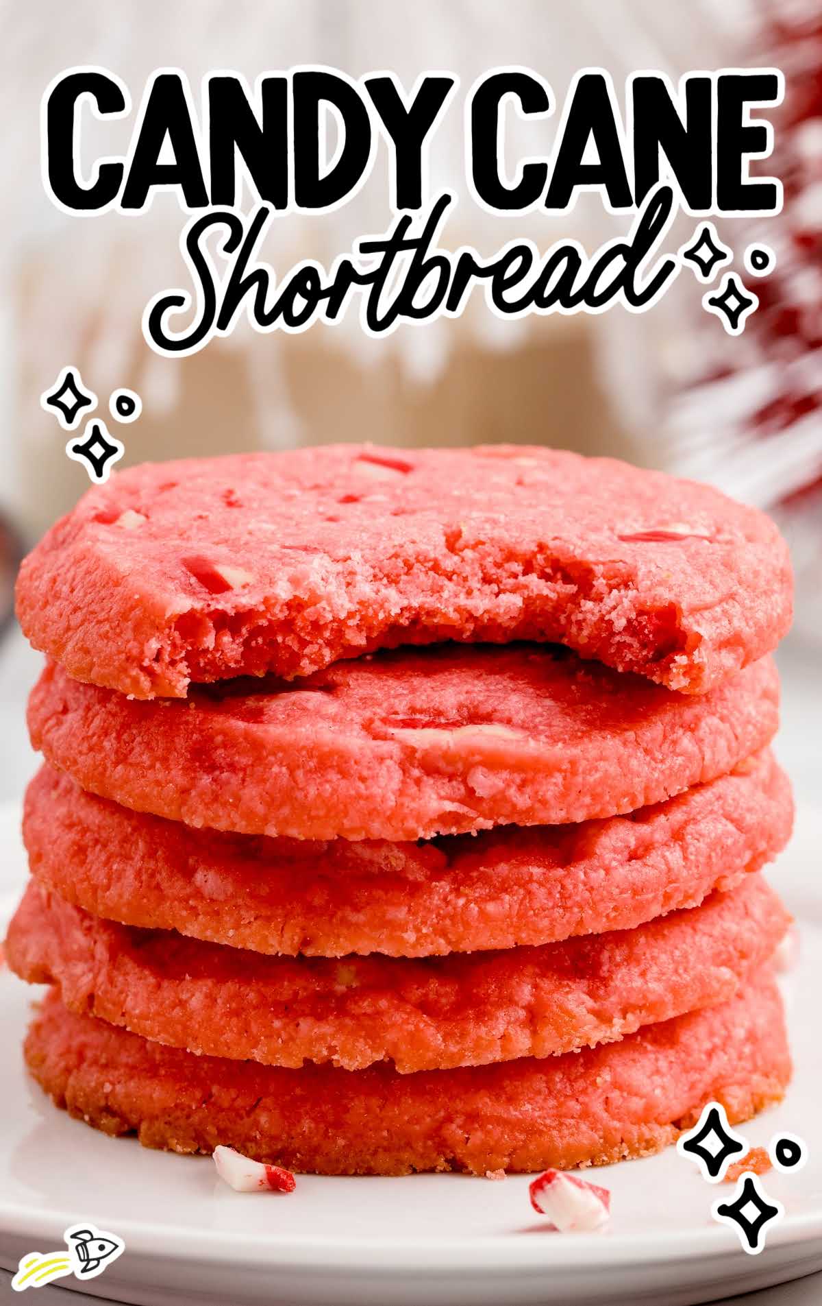close up shot of Candy Cane Shortbread Cookies stacked on top of each other with one having a bite taken out of it on a plate