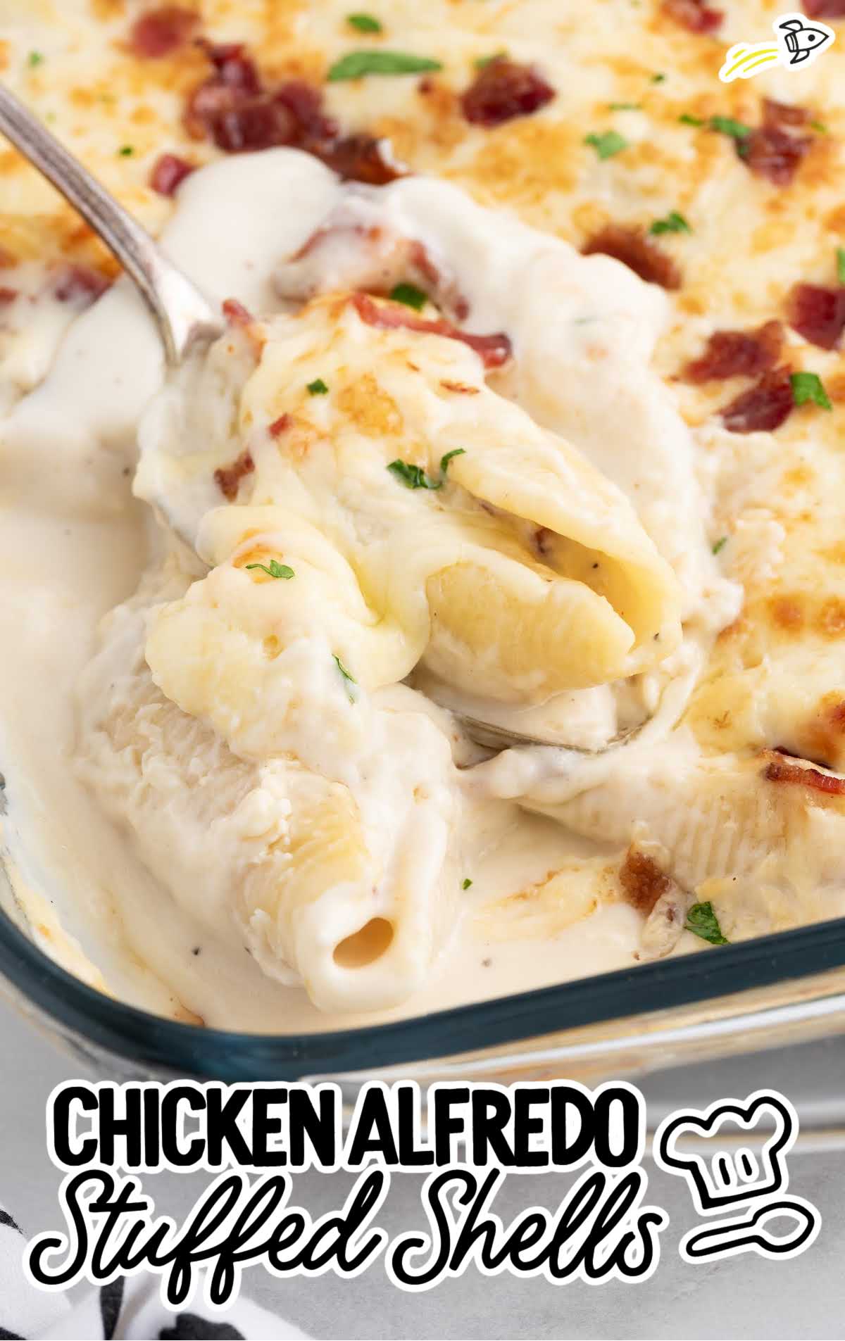 close up shot of Chicken Alfredo Stuffed Shells in a baking dish with a spoon