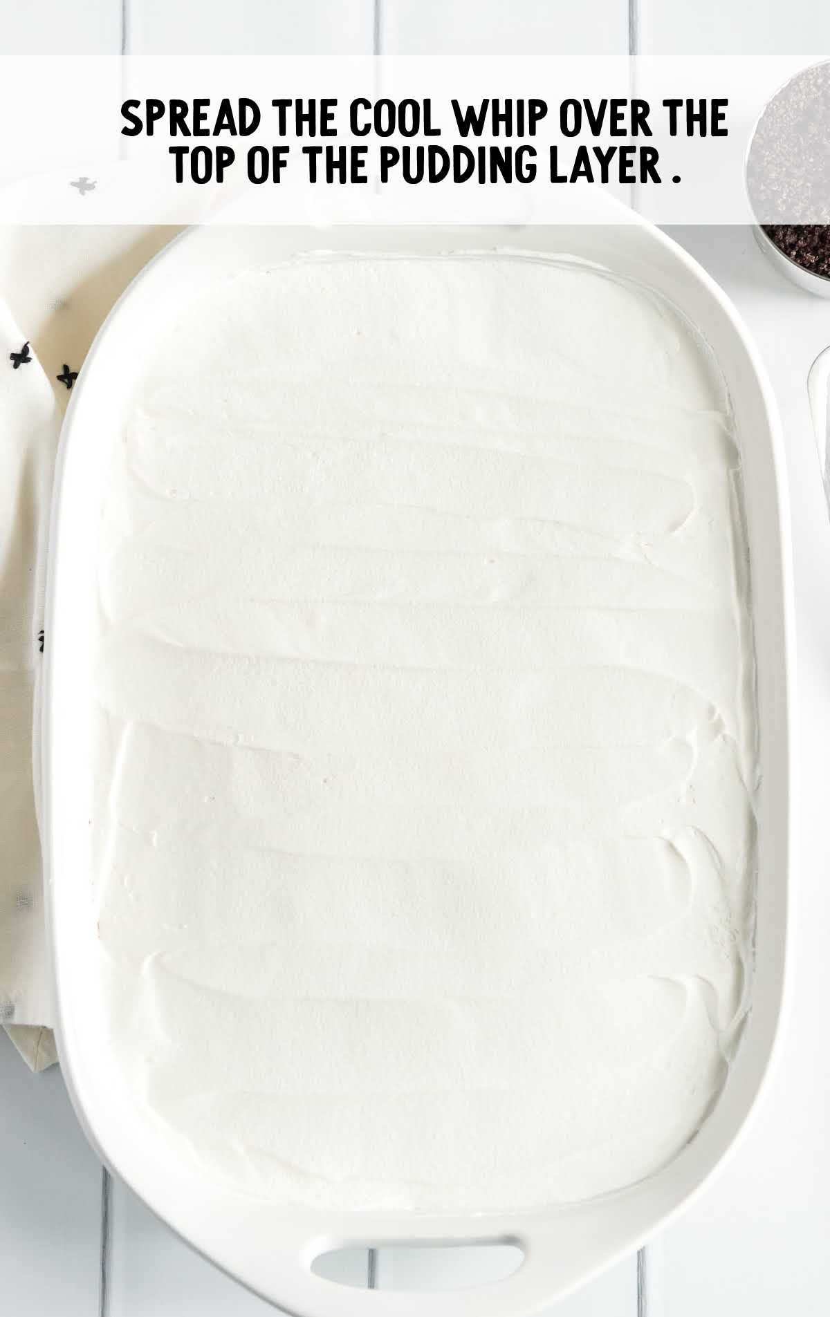 cool whip spread over the top of the pudding layer in a baking dish