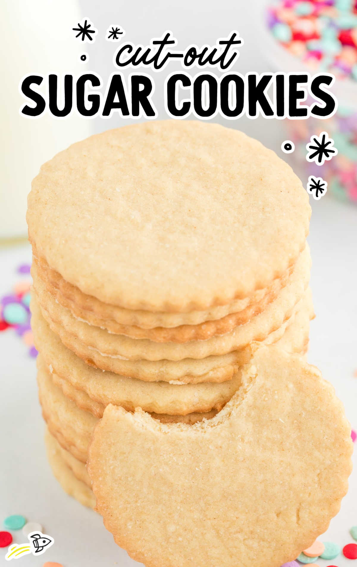 a close up shot of Cut-Out Sugar Cookies stacked on top of each other with one having a bite taken out of it