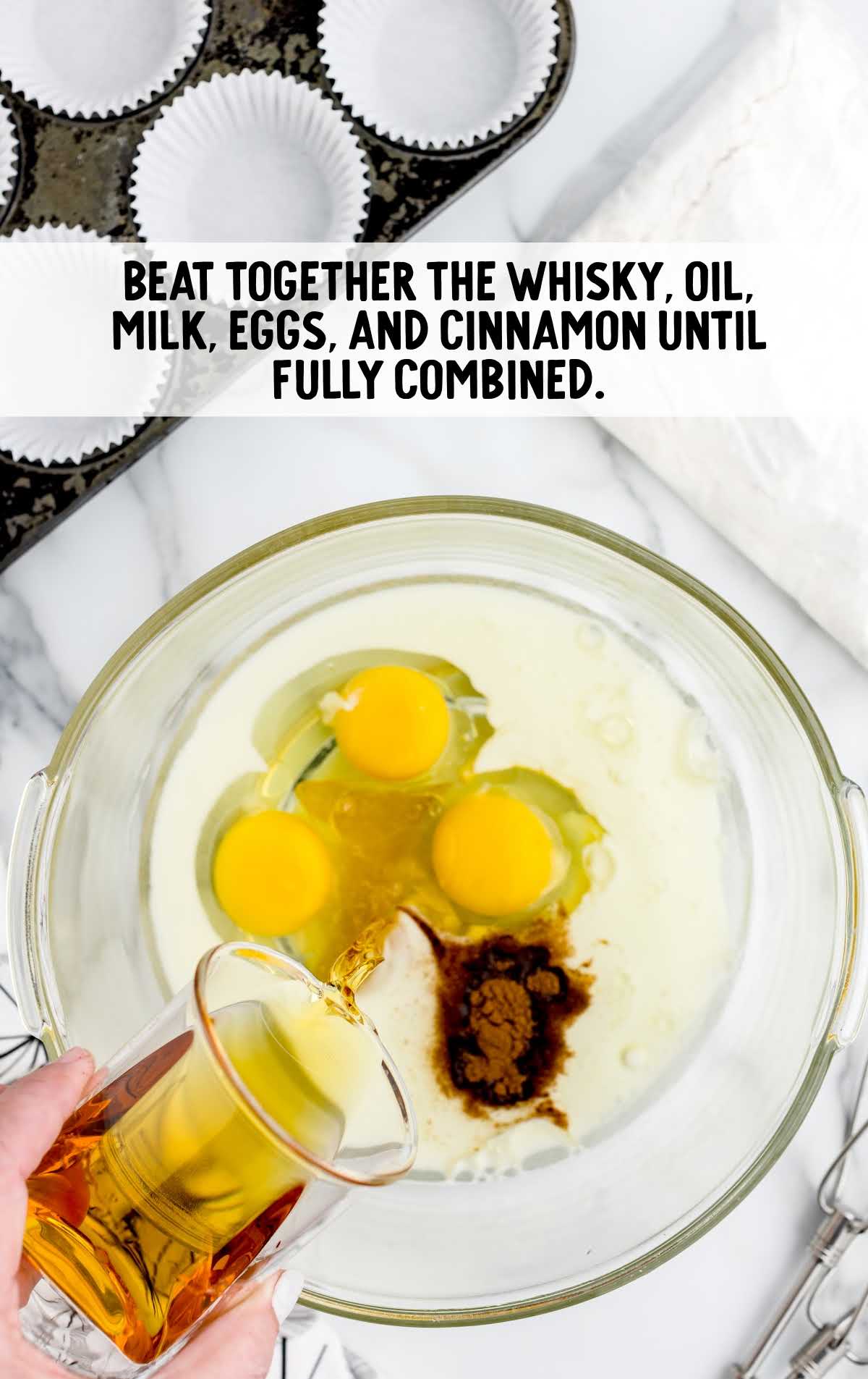 whisky, oil, milk, eggs, and cinnamon combined in a bowl