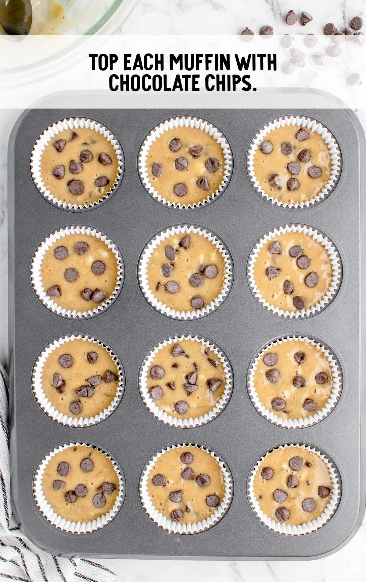 muffin mixture topped with chocolate chips in a muffin pan