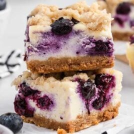 a close up shot of Blueberry Cheesecake Bars stacked on top of each other