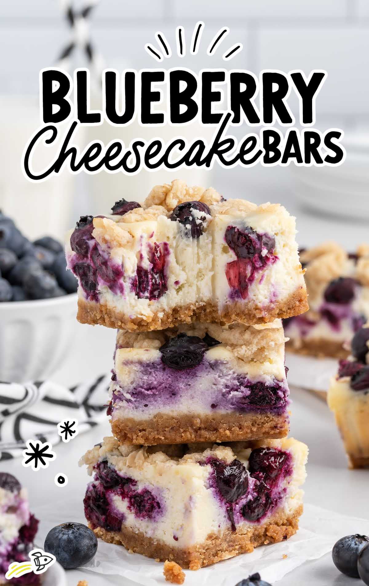 a close up shot of Blueberry Cheesecake Bars stacked on top of each other with one having a bite taken off