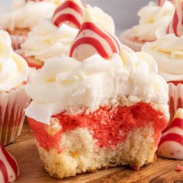 a close up shot of Candy Cane Cupcakes on a wooden board with one having a bite taken out of it