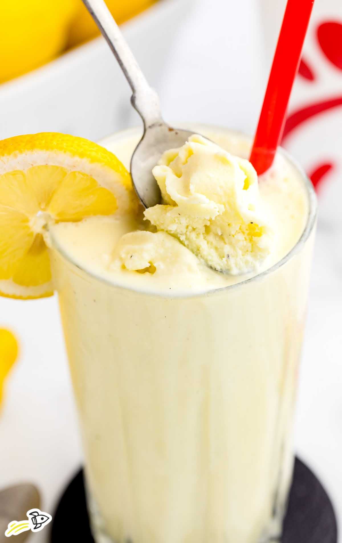 a close up shot of Chick Fil A Lemonade (Frosted) in a tall glass with a spoon grabbing a piece