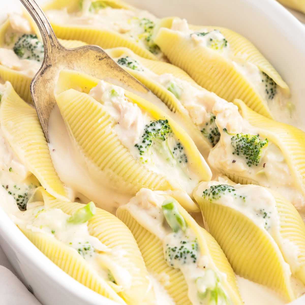 a close up shot of a spoon grabbing one Chicken Broccoli Alfredo Stuffed Shell