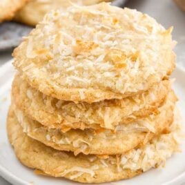 a close up shot of Coconut Cookies stacked on top of each other on a plate