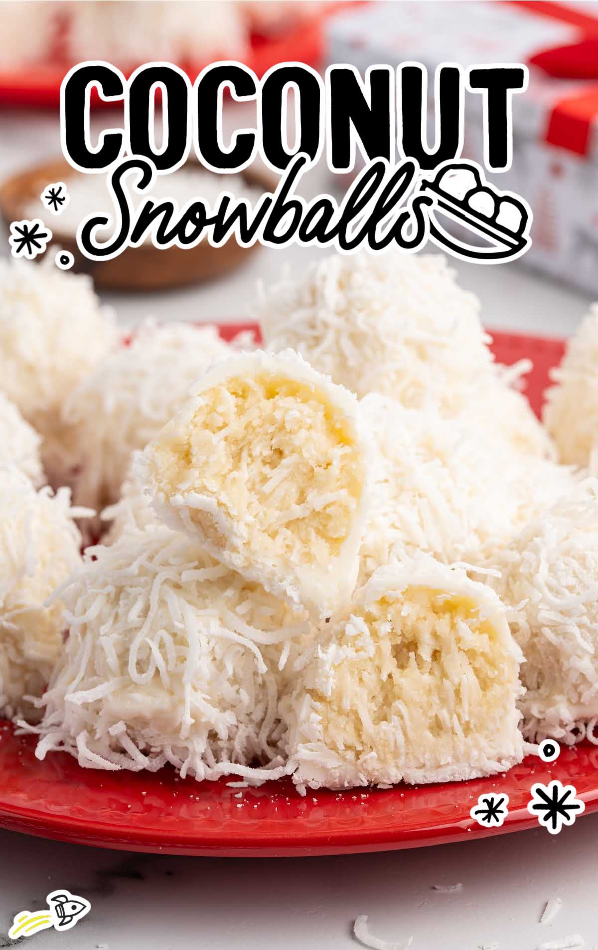 Coconut snowballs on a red plate with one cut open to show the soft creamy center.