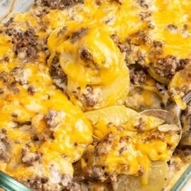 a close up shot of Hamburger Potato Casserole in a baking dish with a piece taken out with a spoon