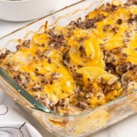 a close up shot of Hamburger Potato Casserole in a baking dish with a piece taken out