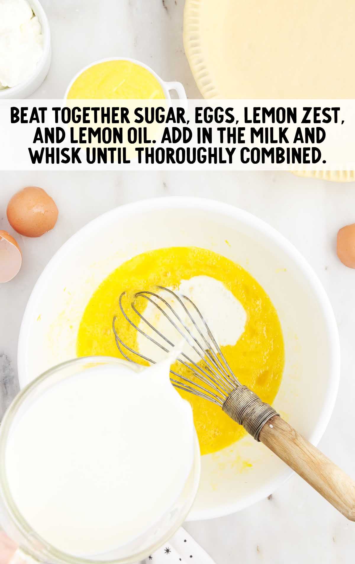 sugar, eggs, lemon zest, and lemon oil whisked in a bowl