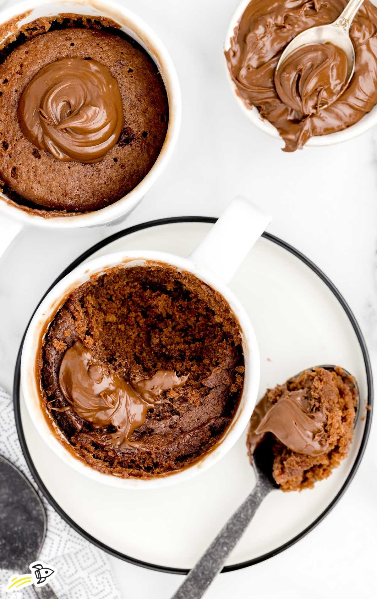 overhead shot of a spoonful of Nutella Mug Cake and Nutella Mug Cake in a mug