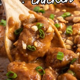 a close up shot of Peanut Butter Chicken in a skillet with a wooden spoon grabbing some