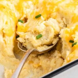 a close up shot of a spoon grabbing a piece of Cheesy Mashed Potatoes