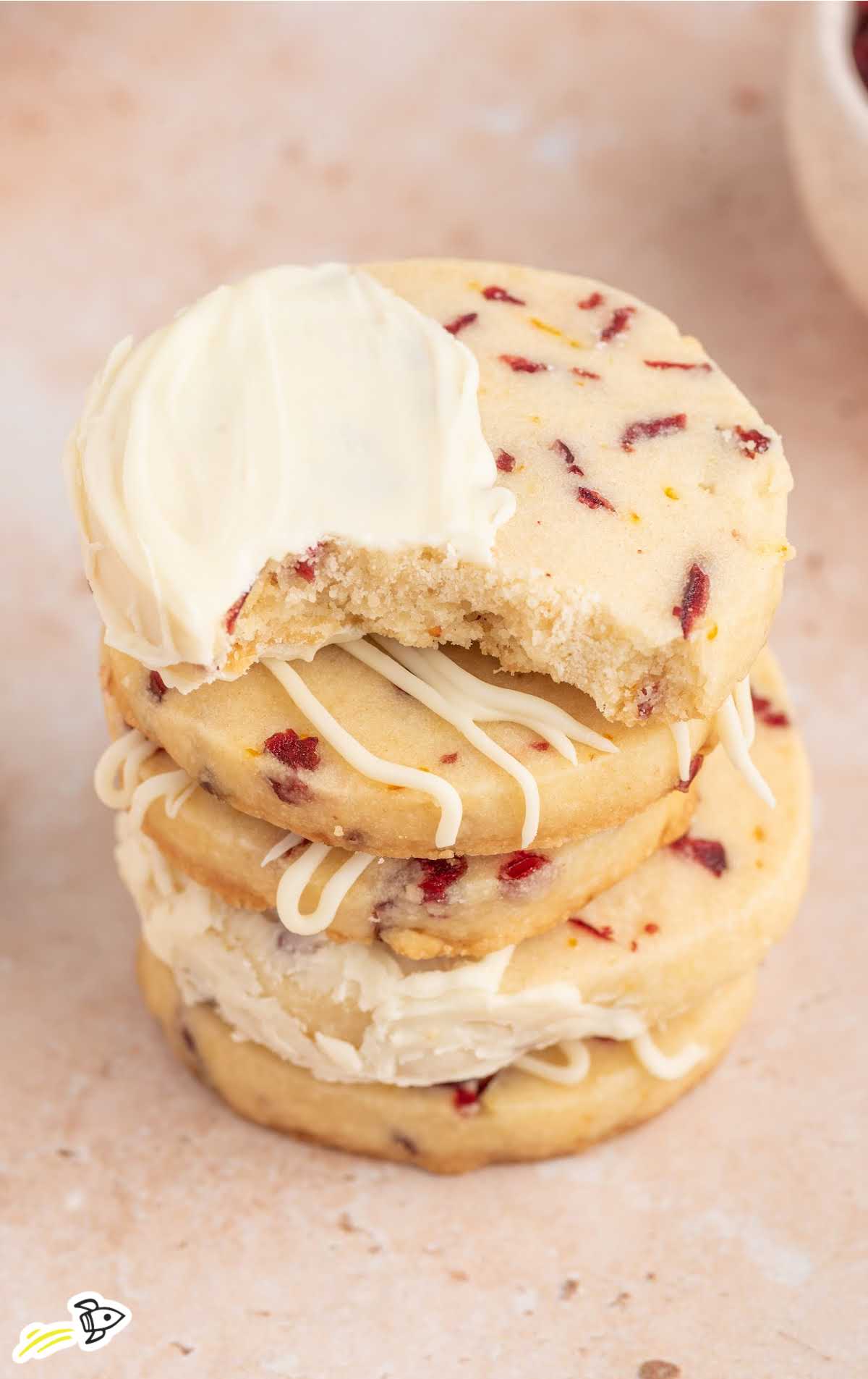 a close up shot of Cranberry Orange Cookies stacked on top of each-other wirth one having a bite taken out of it