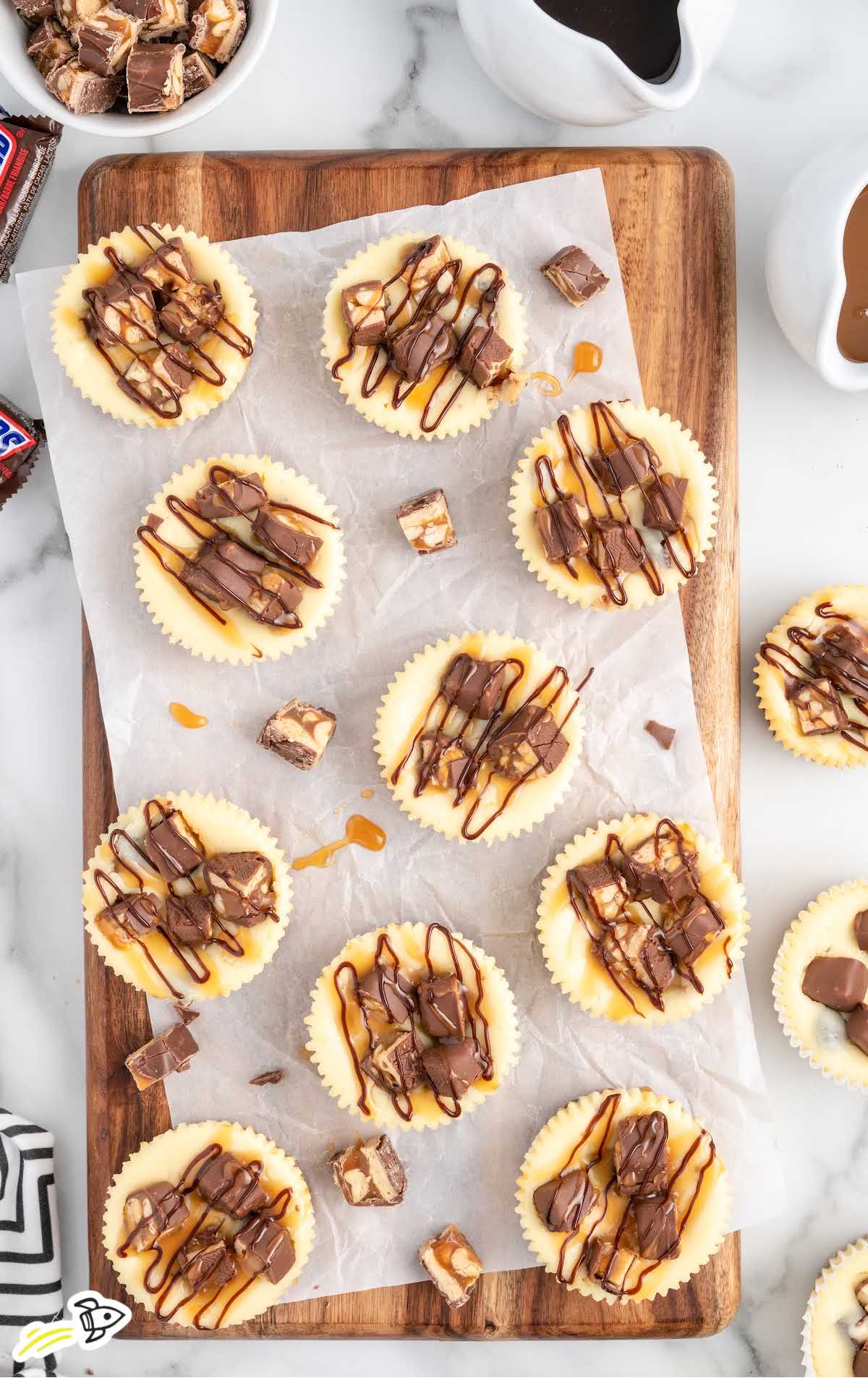 overhead shot of Mini Snickers Cheesecake on a wooden board