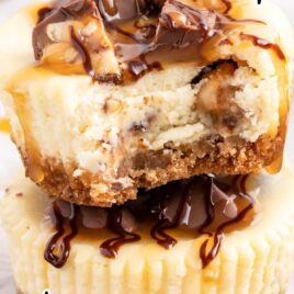 a close up shot of Mini Snickers Cheesecake stacked on top of each other with one having a bite taken out of it
