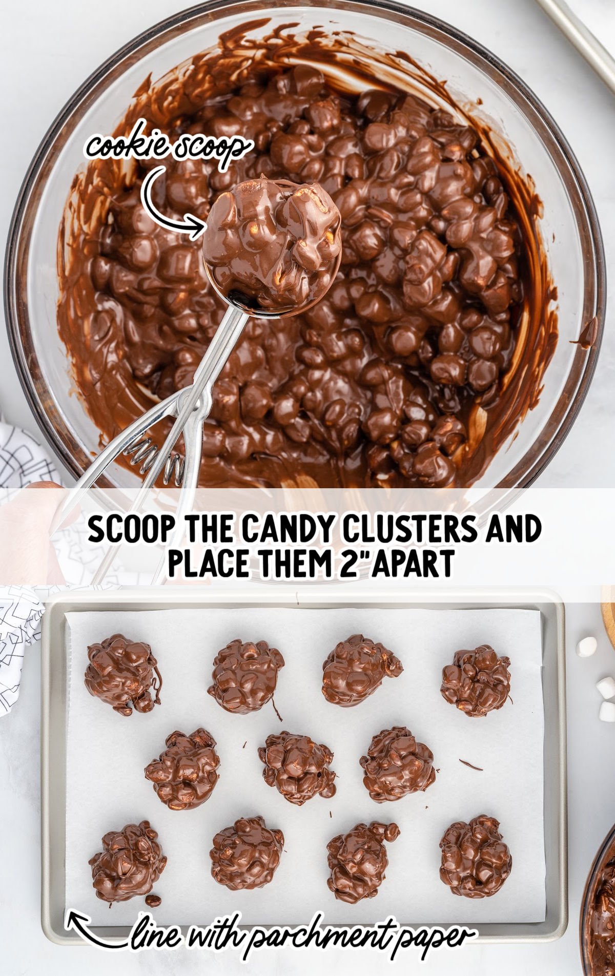A metal cookie scoop lifts a rounded ball of melted chocolate mixed with mini marshmallows and peanuts from a large glass bowl. Below, a parchment-lined baking sheet holds evenly spaced chocolate clusters, about 2 inches apart, ready to chill and set.