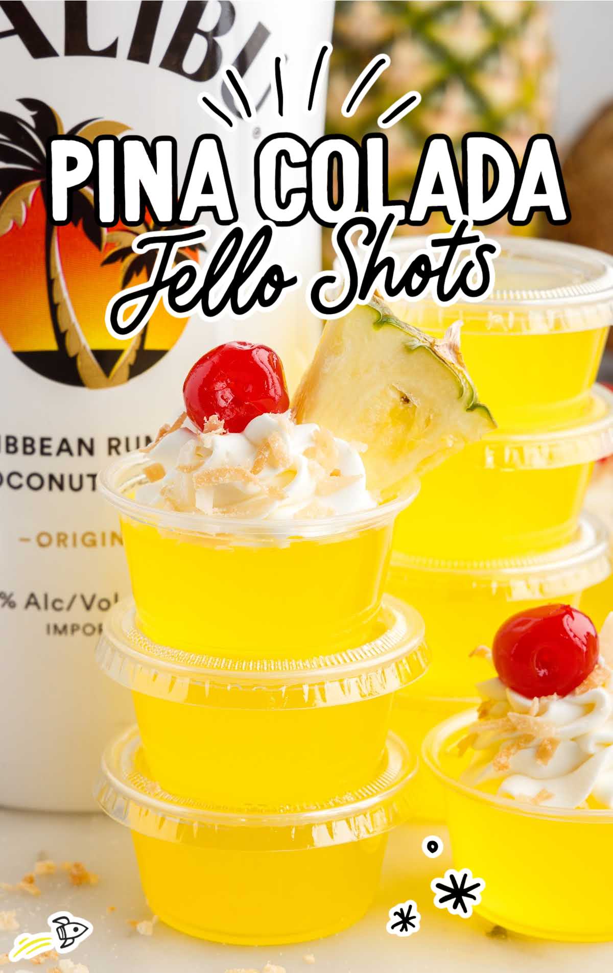 a close up shot of Pina Colada Jello Shots with one topped with a cherry and a slice of pineapple