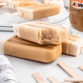 a close up shot of Root Beer Popsicles stacked on top of each other with one having a bite taken out of it