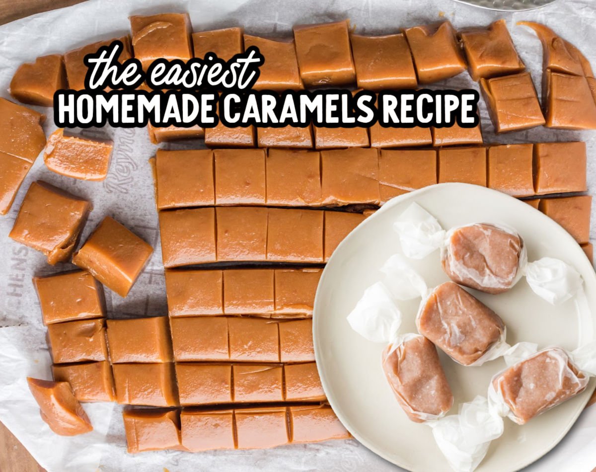 Overhead view of a slab of homemade caramels cut into small squares on parchment paper, with several individually wrapped caramels placed on a white plate.