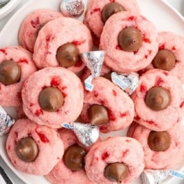 Hand holding half of a cherry kiss cookie showing soft pink inside with cherries