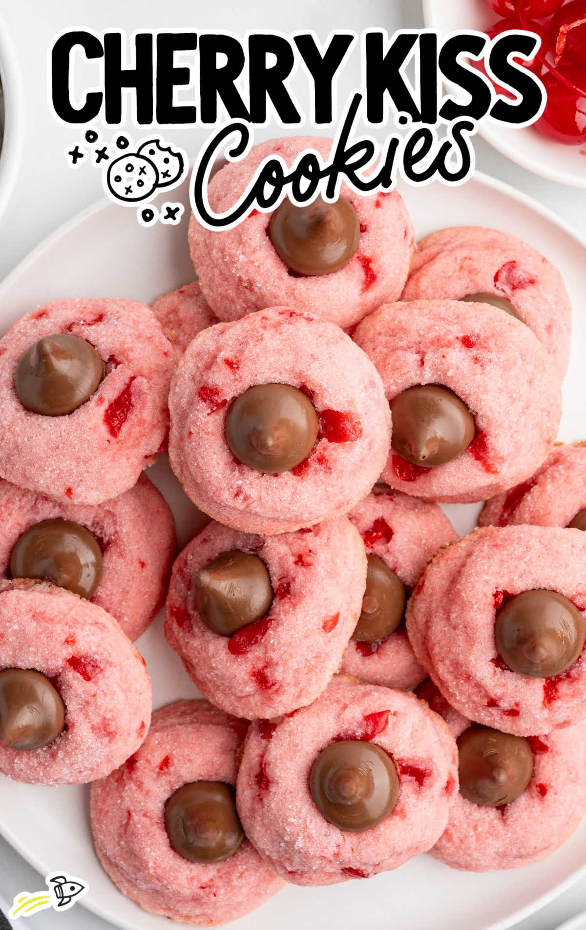 Close-up of a cherry kiss cookie topped with a Hershey’s Kiss on a white plate