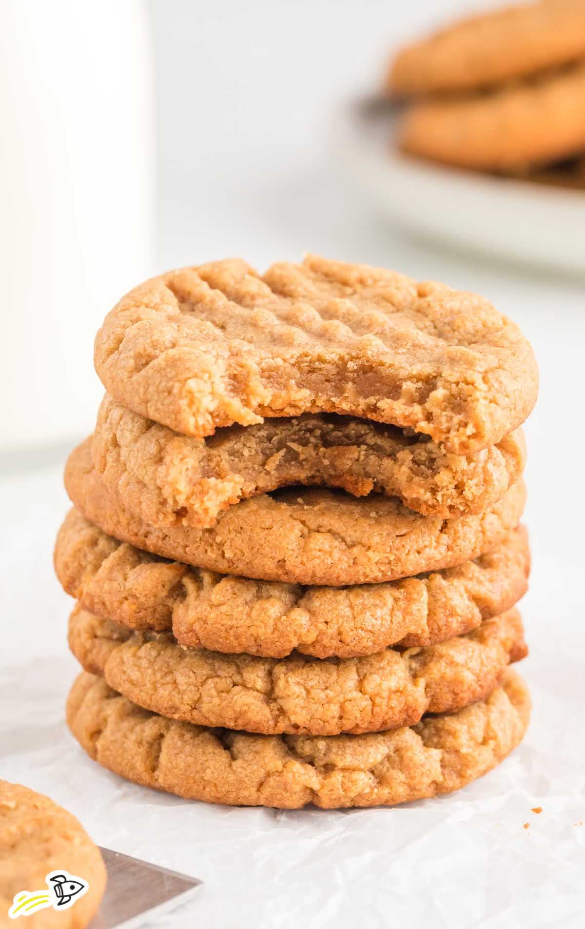 a close up shot of 3 Ingredient Peanut Butter Cookies stacked on top of each other with a couple of cookies having a bite take out of it