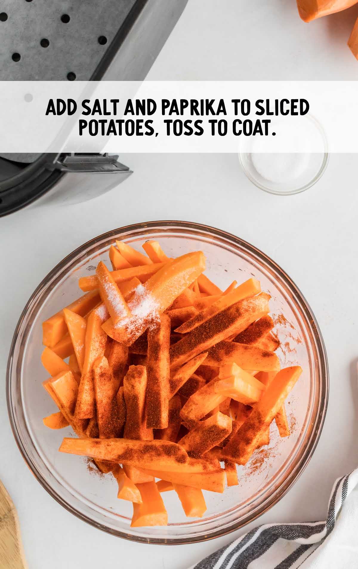 salt and paprika added to the sliced potatoes